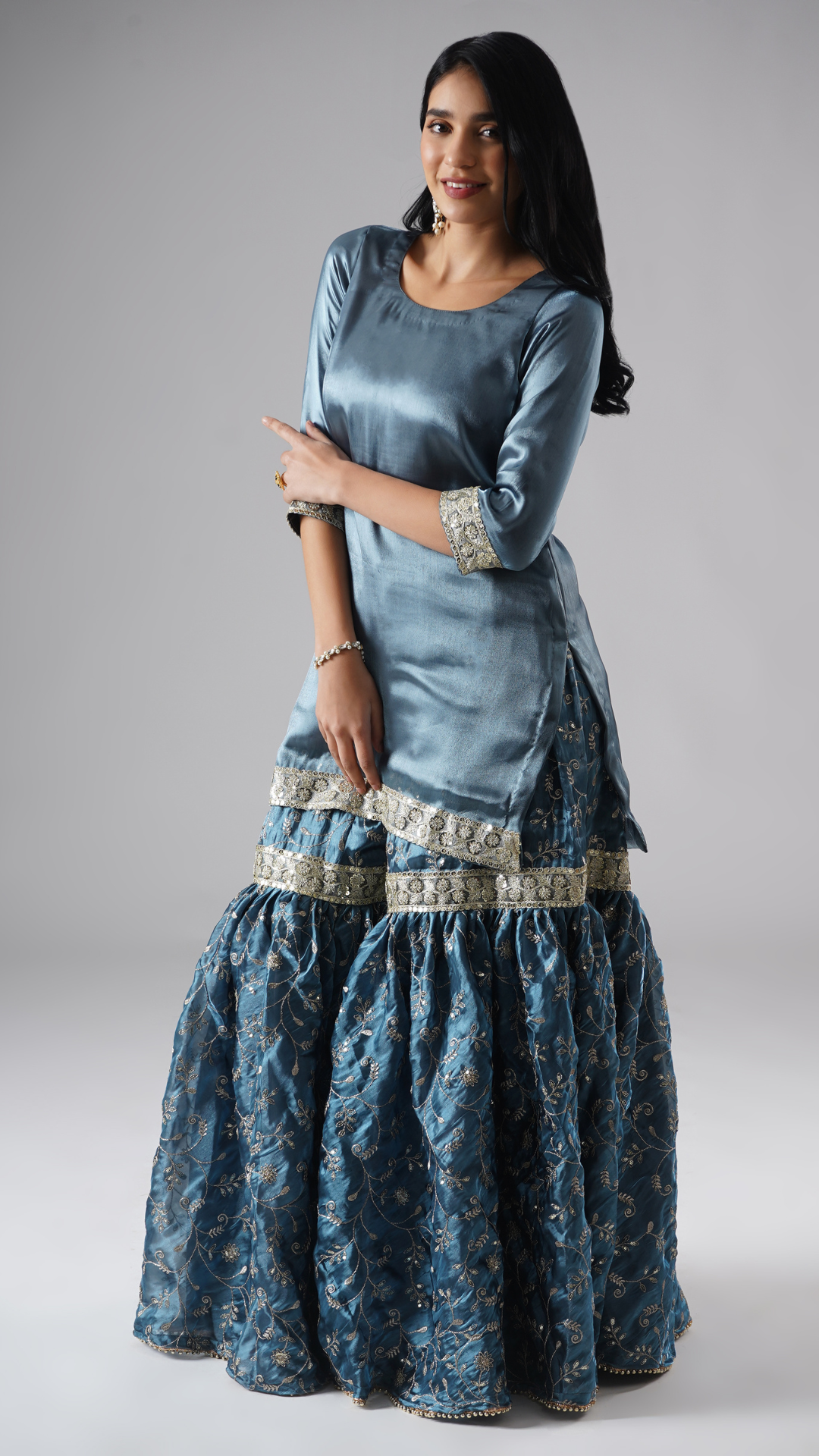 Side view of model wearing Zahrat’s Tehzeeb-e-Aab teal blue gharara set without dupatta, highlighting the gharara flare and kurta.