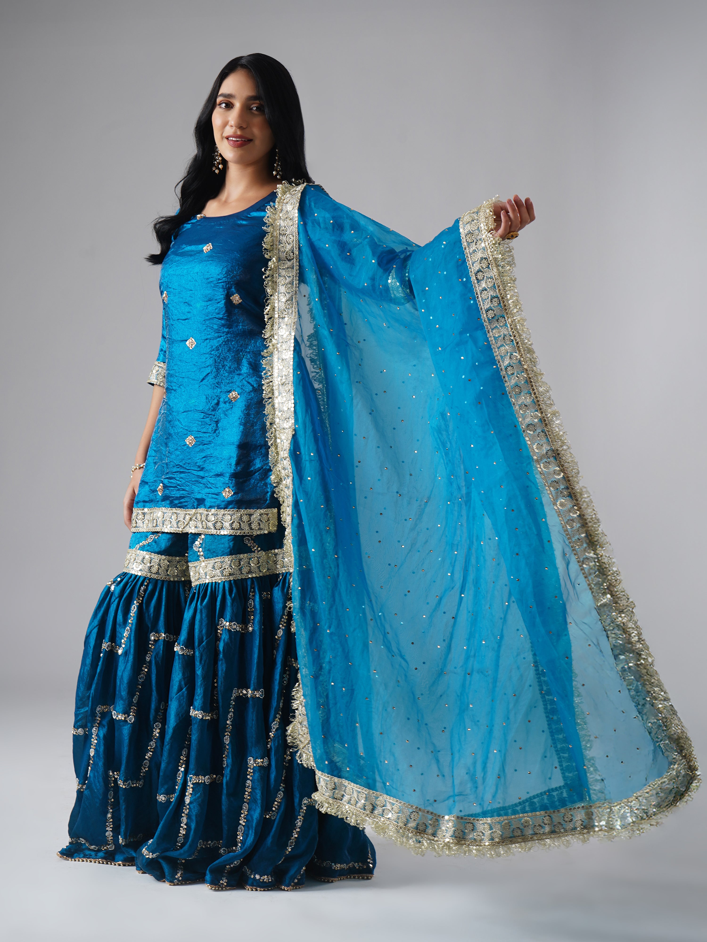 Model styled in the Neelafshan – The Teal Sapphire gharara set by Zahrat, side view highlighting the full-length dupatta and the entire outfit.