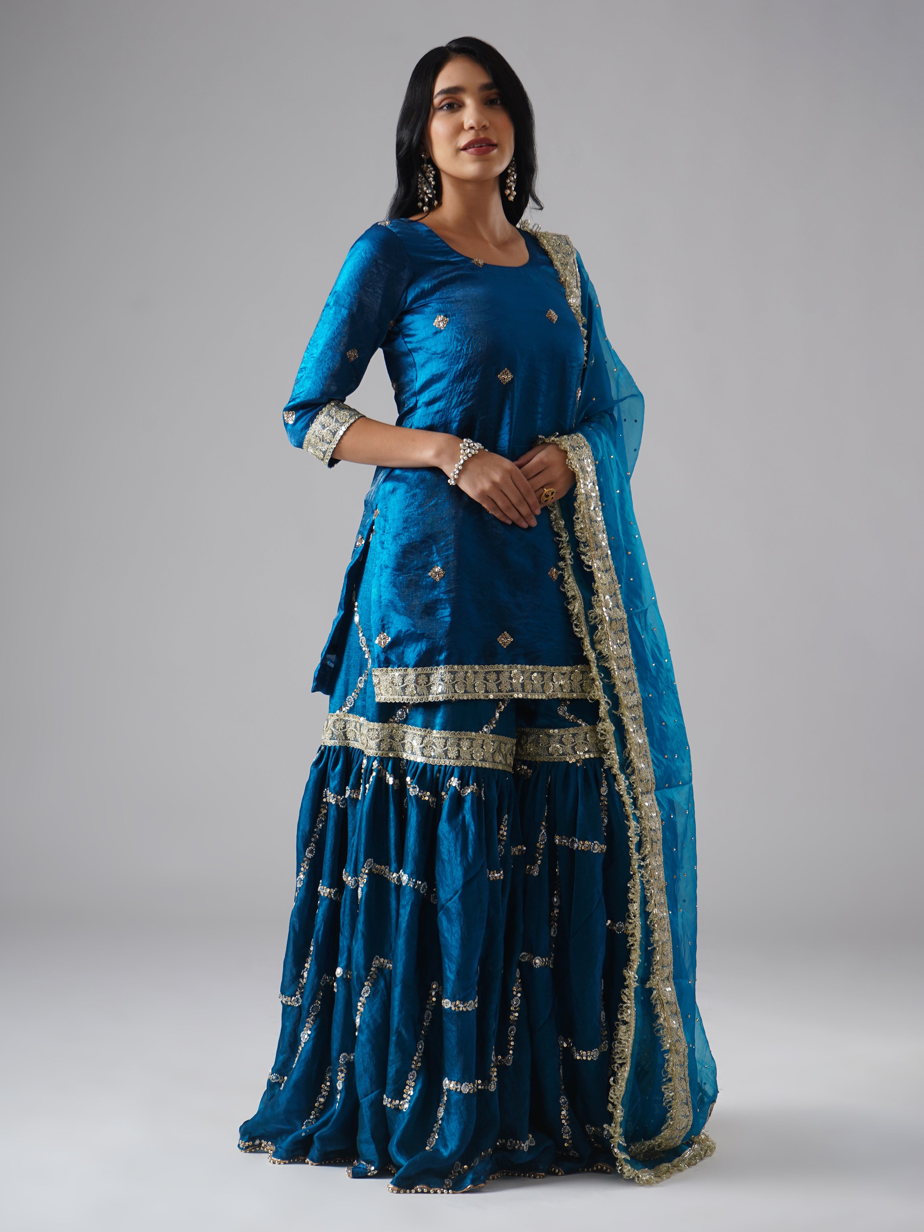 Right side view of model wearing Zahrat’s Neelafshan – The Teal Sapphire gharara set, showcasing the complete ensemble with gharara, kurta, and dupatta.