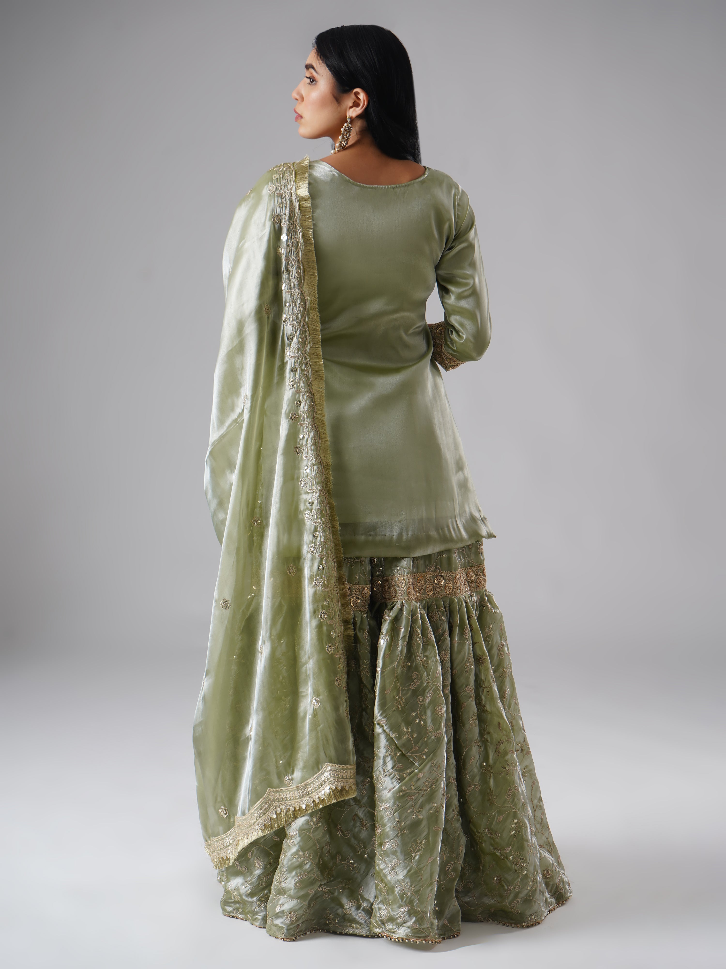 Model styled in the Mehr-e-Zaytuni – The Olive Whisper gharara set by Zahrat, back view highlighting the full outfit and draped dupatta.