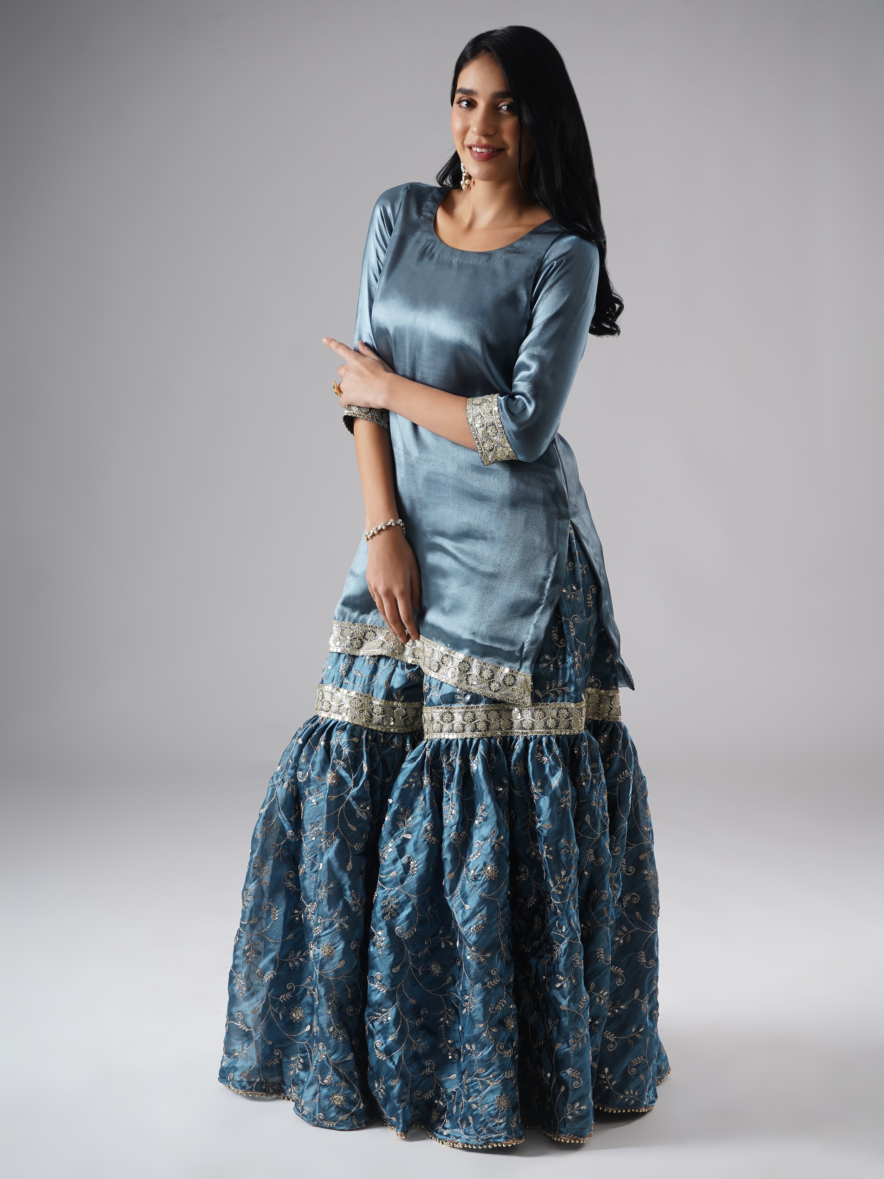 Side view of model wearing Zahrat’s Tehzeeb-e-Aab teal blue gharara set without dupatta, highlighting the gharara flare and kurta.