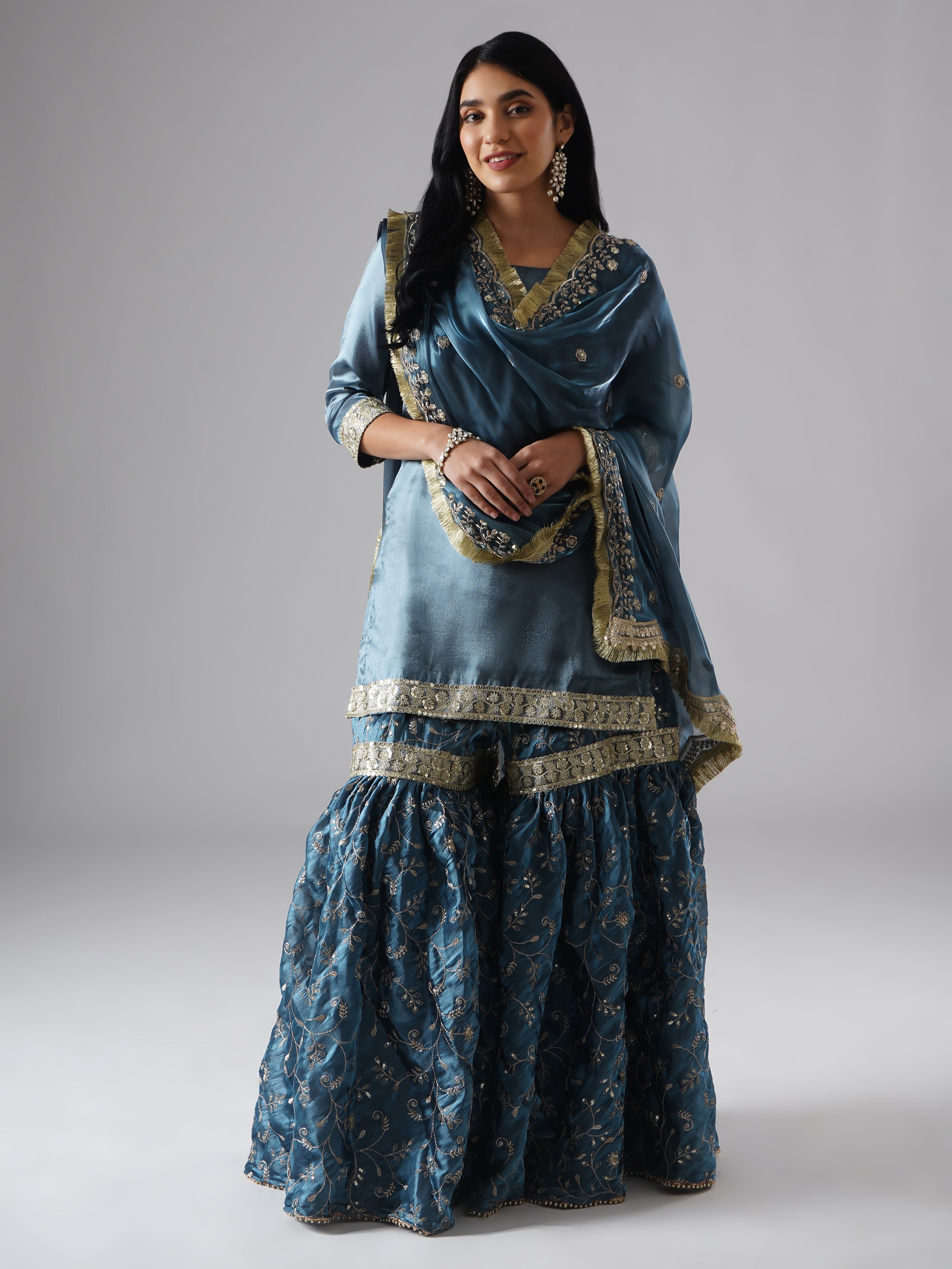 Front view of model wearing Zahrat’s Tehzeeb-e-Aab teal blue gharara set, styled with draped dupatta, showcasing the complete ensemble.