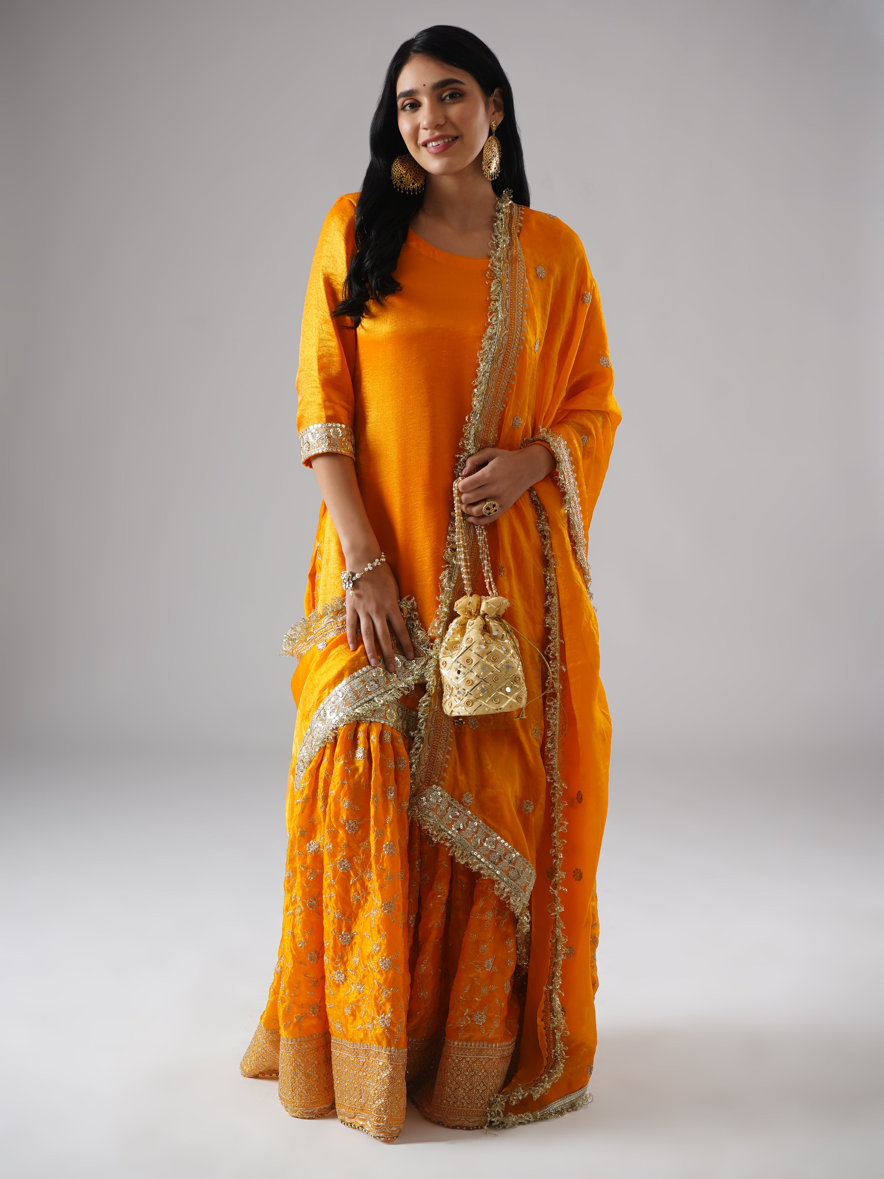 Model wearing Zahrat’s Mehrigold gharara set, front view, showcasing the full silhouette with matching potli bag.