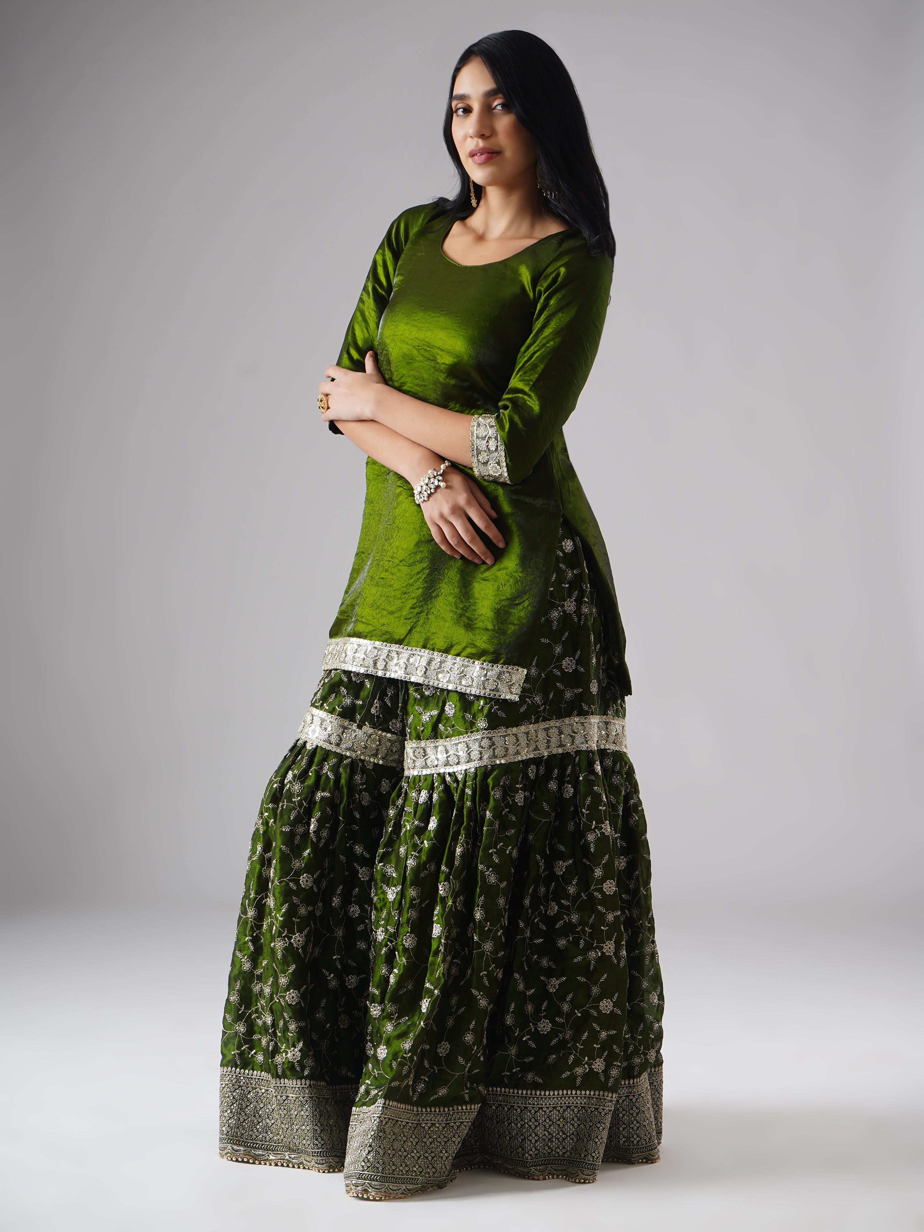 Side view of model wearing Zahrat’s Khushrang Henna jewel-toned henna green gharara set without dupatta, highlighting the gharara flare and kurta.