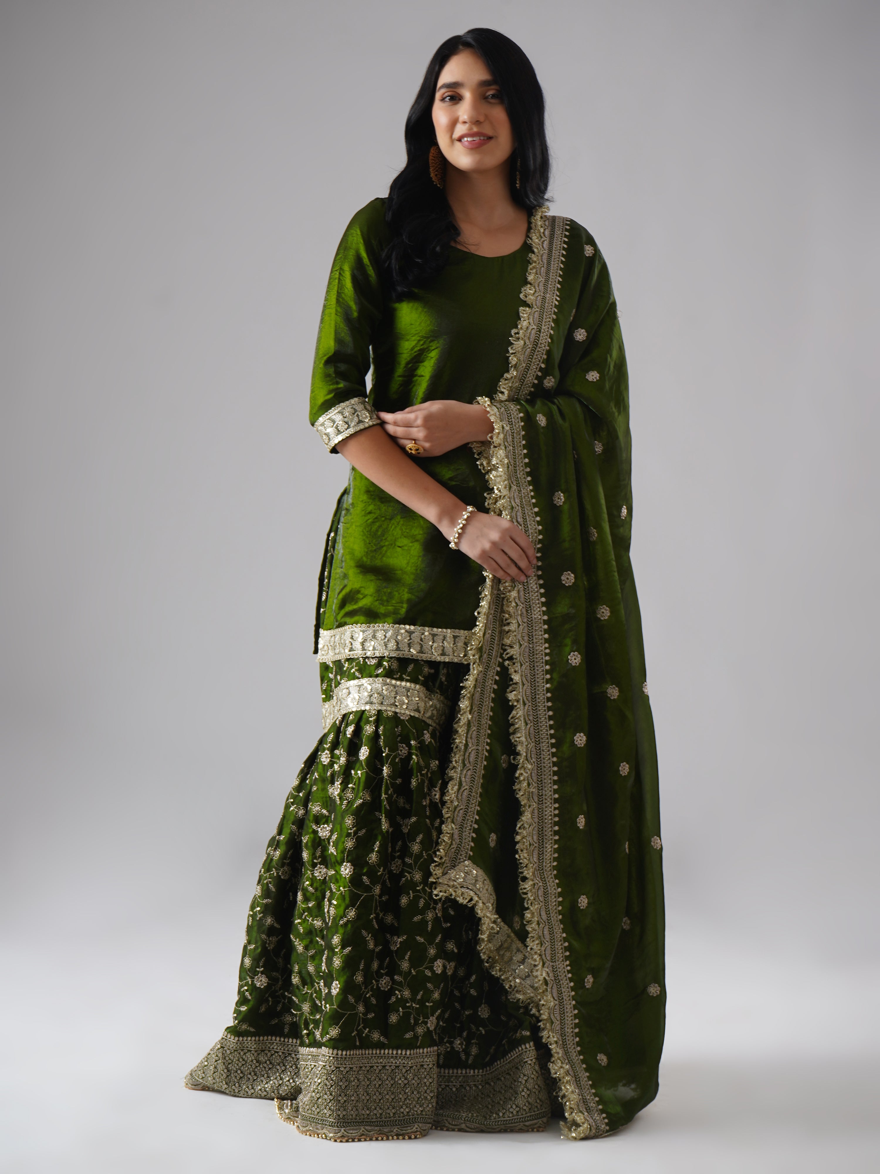Model styled in the Khushrang Henna Gharara by Zahrat, jewel-toned henna green, front view highlighting the full outfit including gharara, kurta, and dupatta.