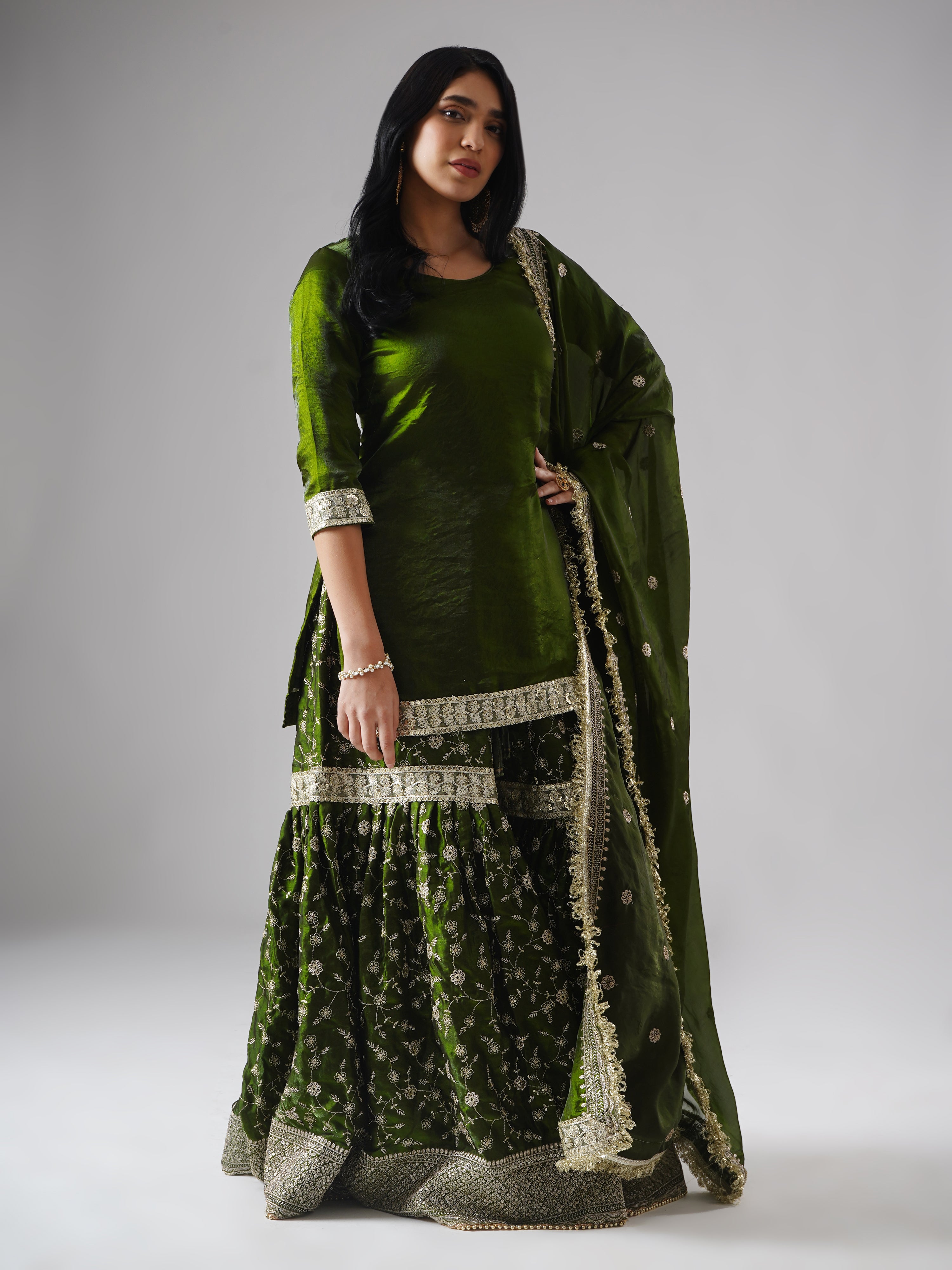 Right side view of model wearing Zahrat’s Khushrang Henna jewel-toned henna green gharara set, showcasing the complete ensemble with gharara, kurta, and dupatta.