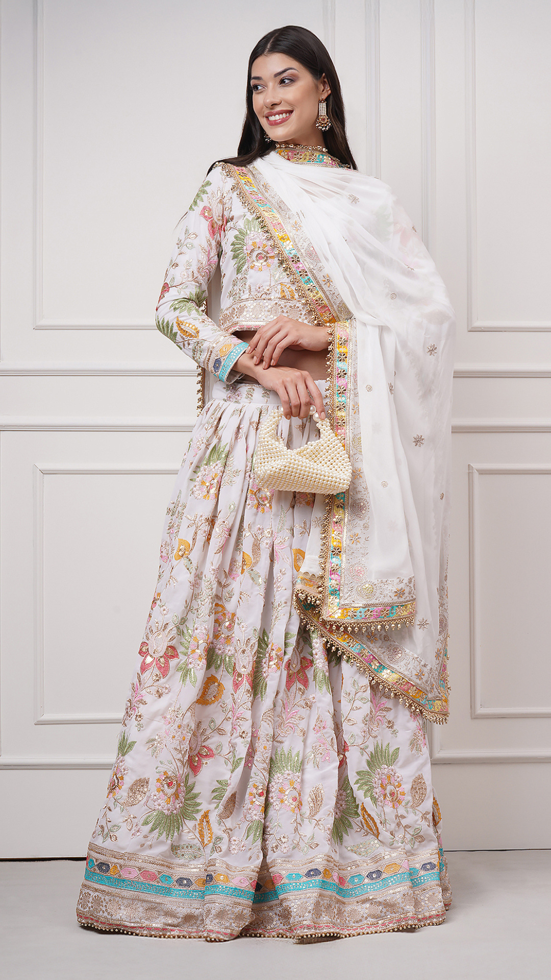 Front side view of a model wearing Eira Bloom Lehenga Set with a potli bag - Zahrat White Embroidered Lehenga 