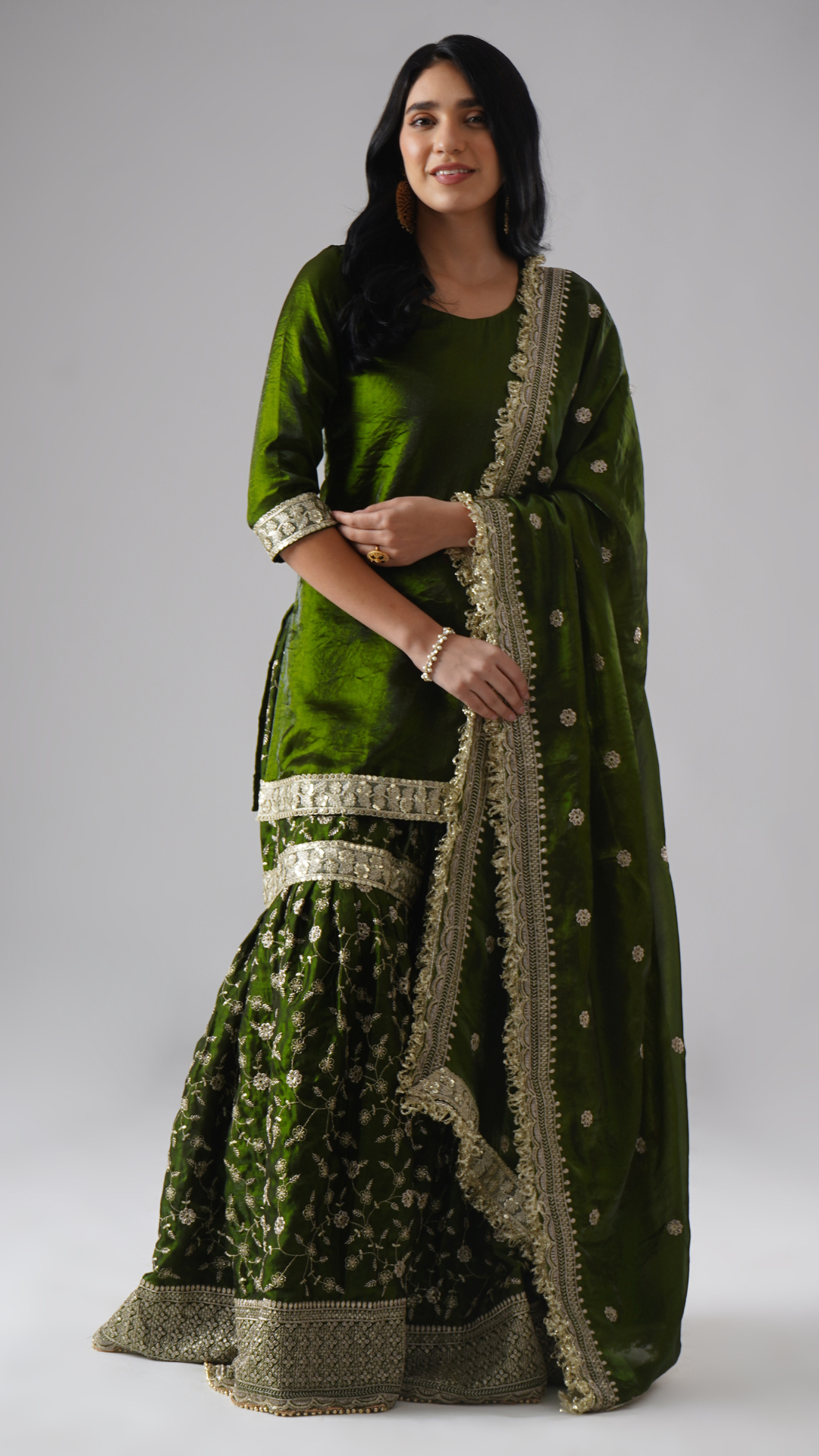 Model styled in the Khushrang Henna Gharara by Zahrat, jewel-toned henna green, front view highlighting the full outfit including gharara, kurta, and dupatta.