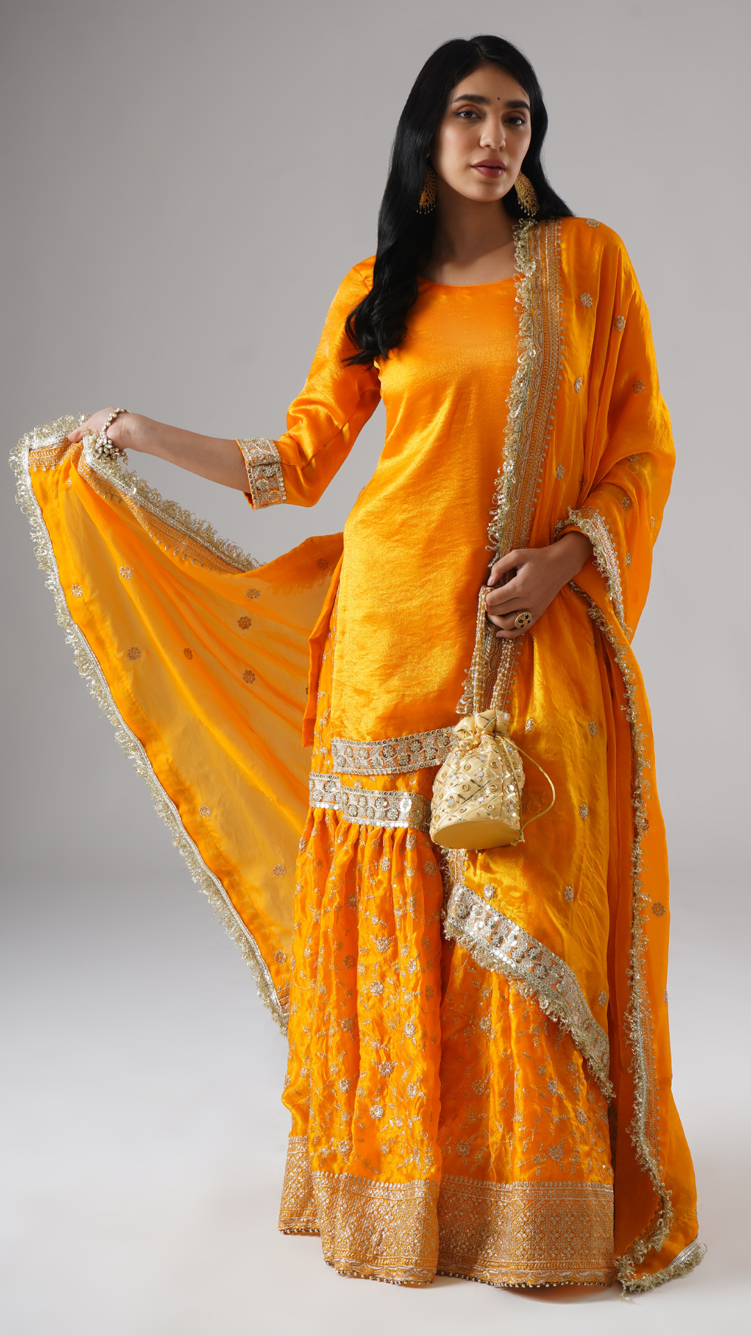 Model wearing Zahrat’s Mehrigold gharara set, front view, showcasing the full silhouette with matching potli bag and dupatta.