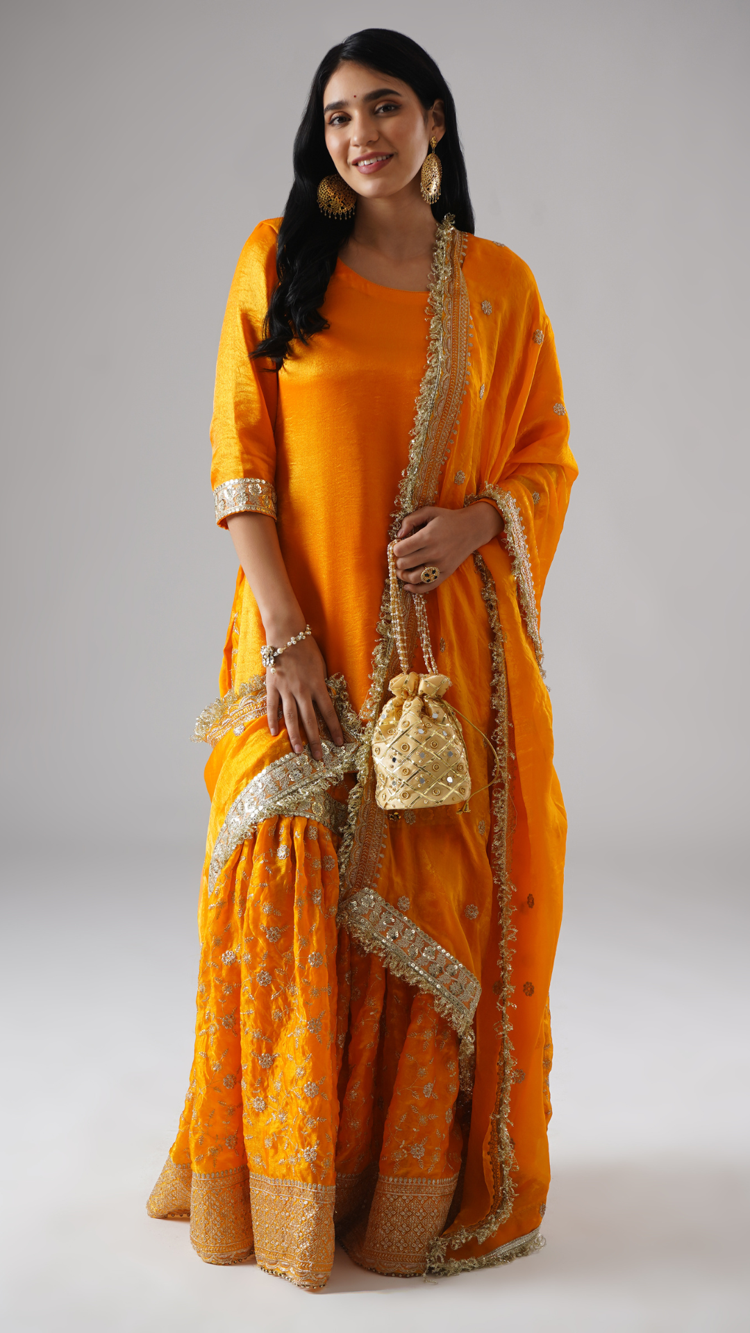 Model wearing Zahrat’s Mehrigold gharara set, front view, showcasing the full silhouette with matching potli bag.