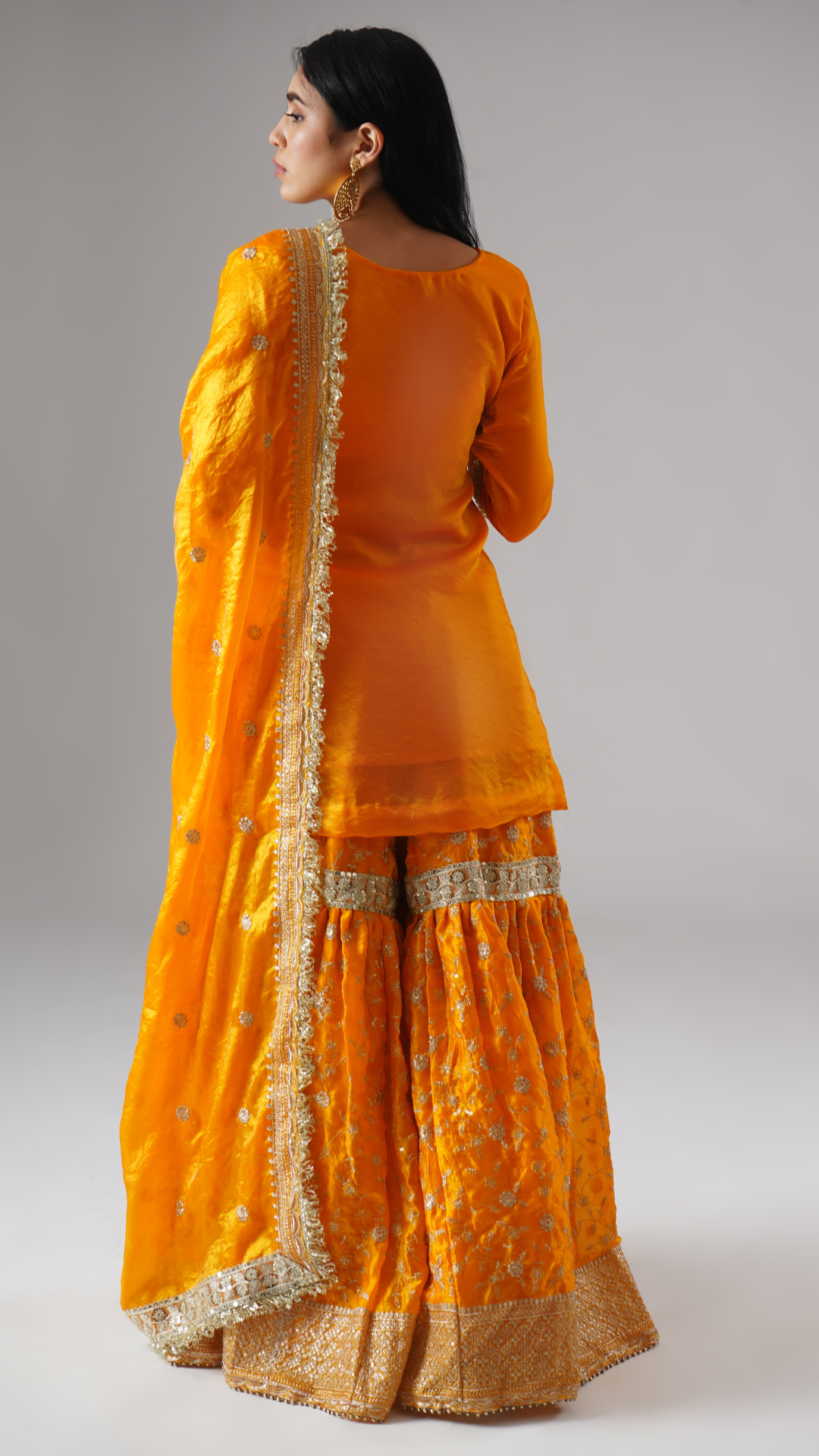 Model styled in the Mehrigold gharara set by Zahrat, back view highlighting the full outfit and dupatta drape.