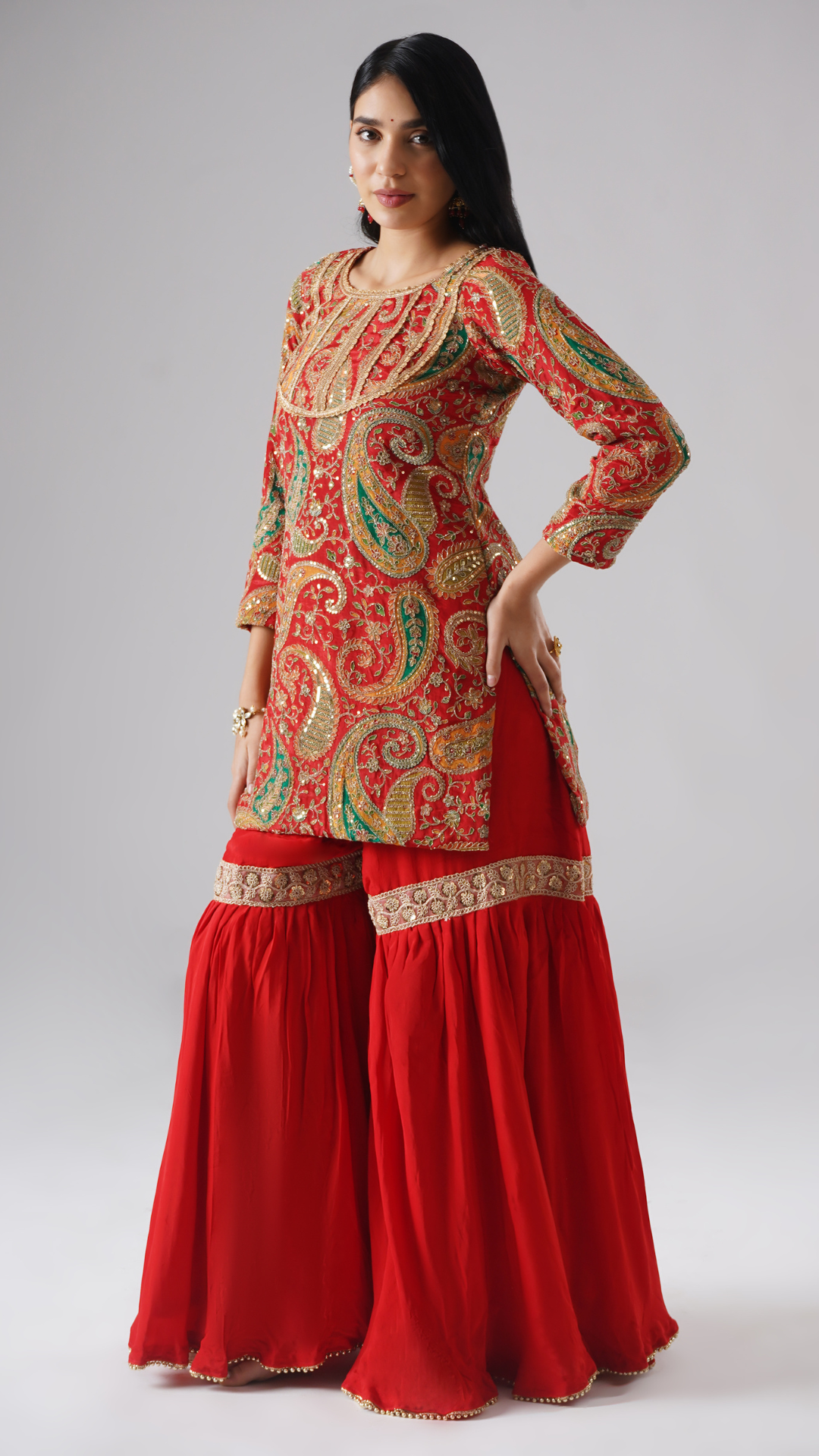 Side view of model wearing Zahrat’s Mehroza crimson red gharara set without dupatta, highlighting the gharara flare and kurta.