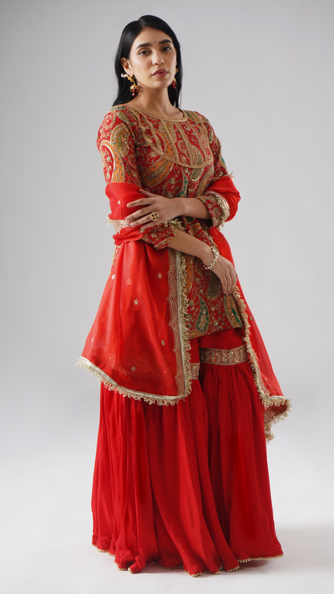 Right side view of model wearing Zahrat’s Mehroza crimson red gharara set, showcasing the complete ensemble with gharara, kurta, and dupatta.