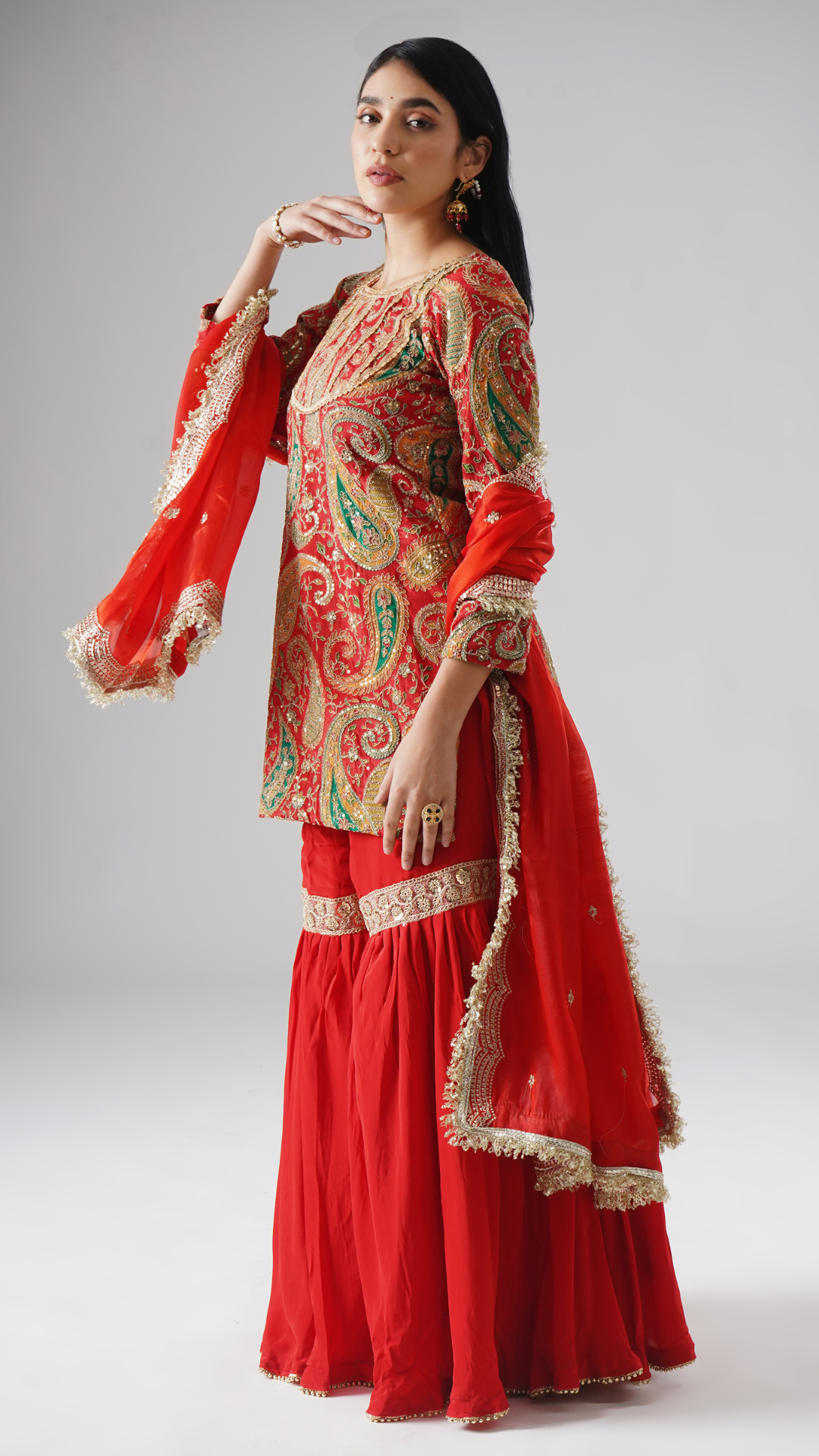 Left side view of model wearing Zahrat’s Mehroza crimson red gharara set, showcasing the complete ensemble with gharara, kurta, and dupatta.