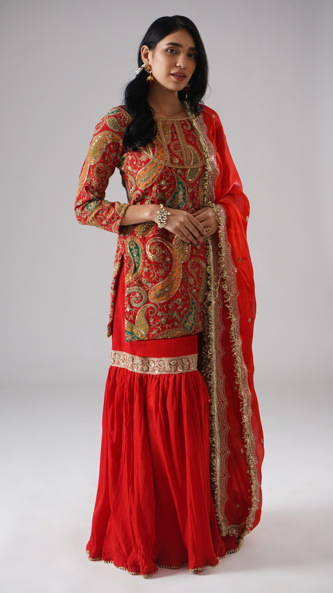 Alternate right side view of model wearing Zahrat’s Mehroza crimson red gharara set, showcasing the complete ensemble with gharara, kurta, and dupatta.