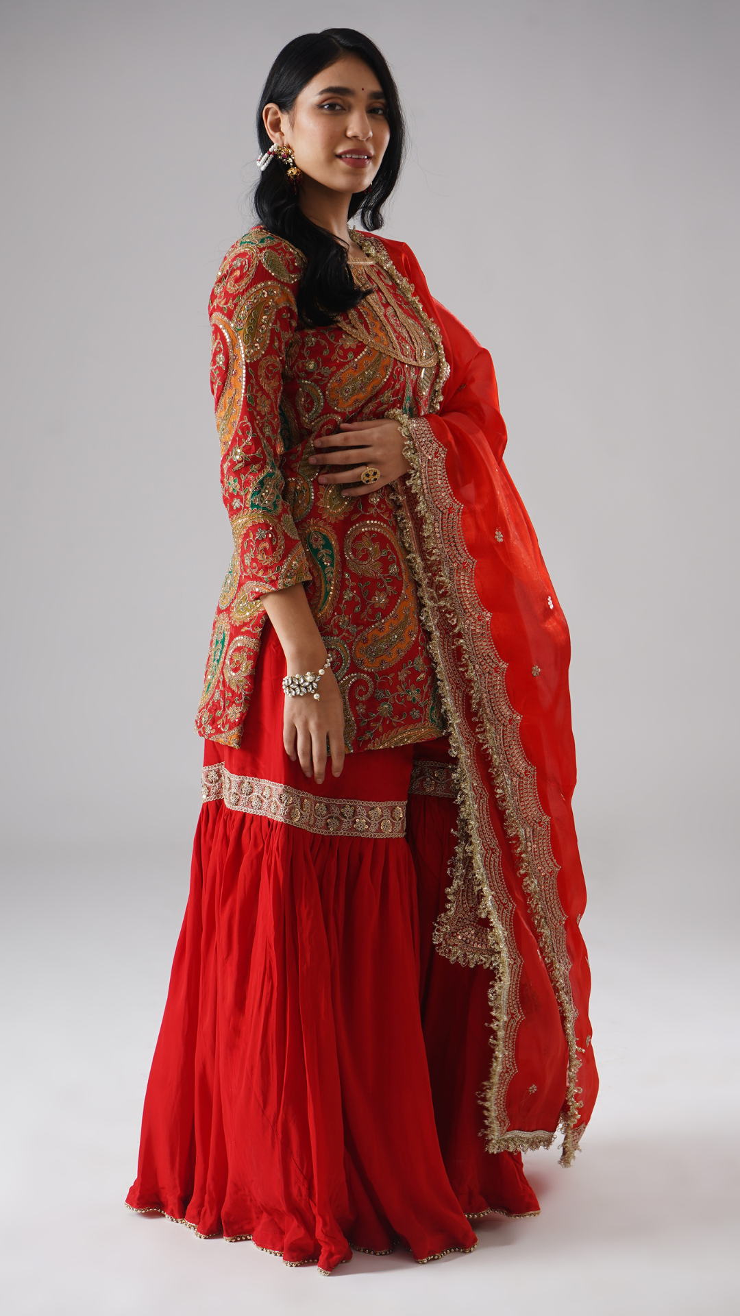 Model styled in the Mehroza crimson red gharara by Zahrat, right side view highlighting the draped dupatta and full outfit.