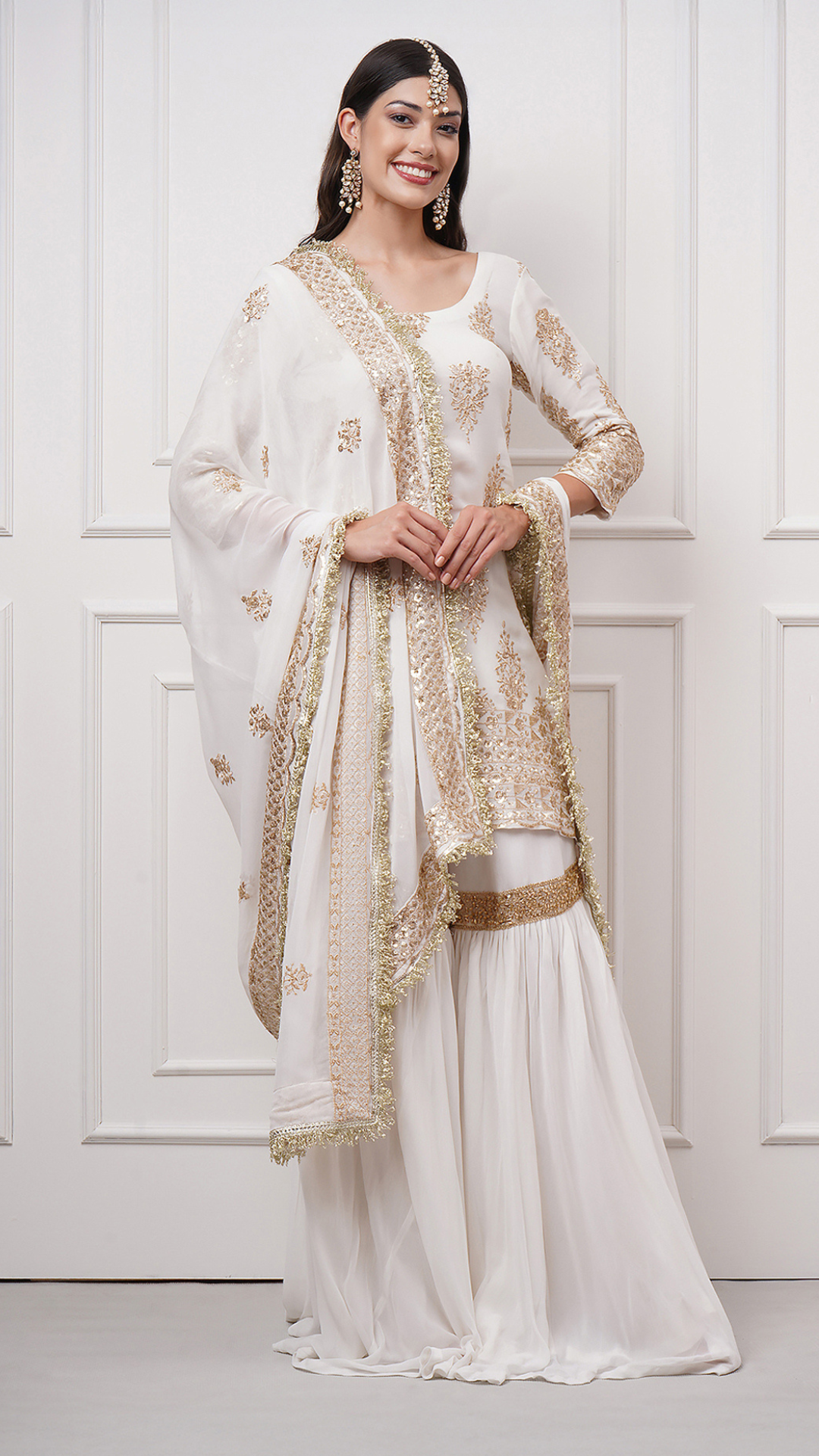 A woman models in Naura – White Embroidered Gharara Set by Zahrat -front view.