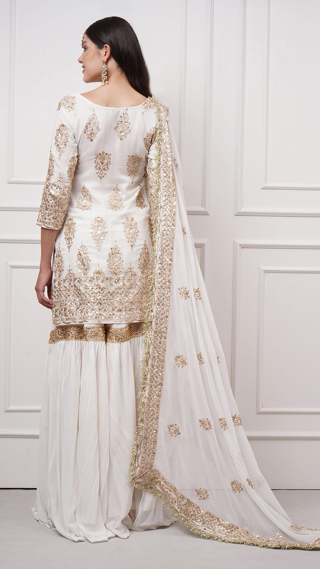 Back side view of a model in Naura – White Embroidered Gharara Set by Zahrat.