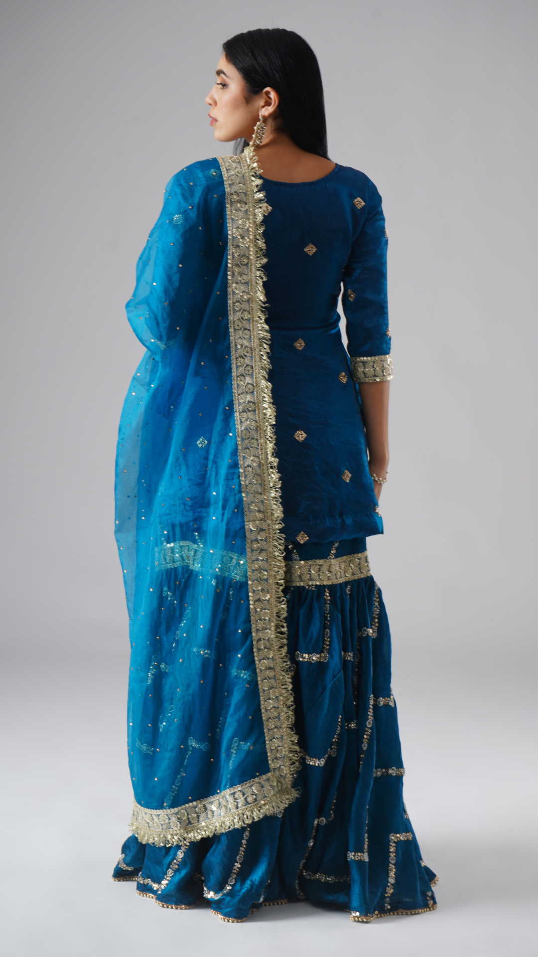 Model styled in the Neelafshan – The Teal Sapphire gharara set by Zahrat, back view highlighting the full outfit and draped dupatta.