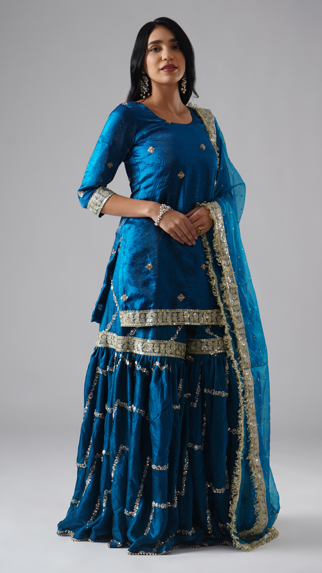 Right side view of model wearing Zahrat’s Neelafshan – The Teal Sapphire gharara set, showcasing the complete ensemble with gharara, kurta, and dupatta.