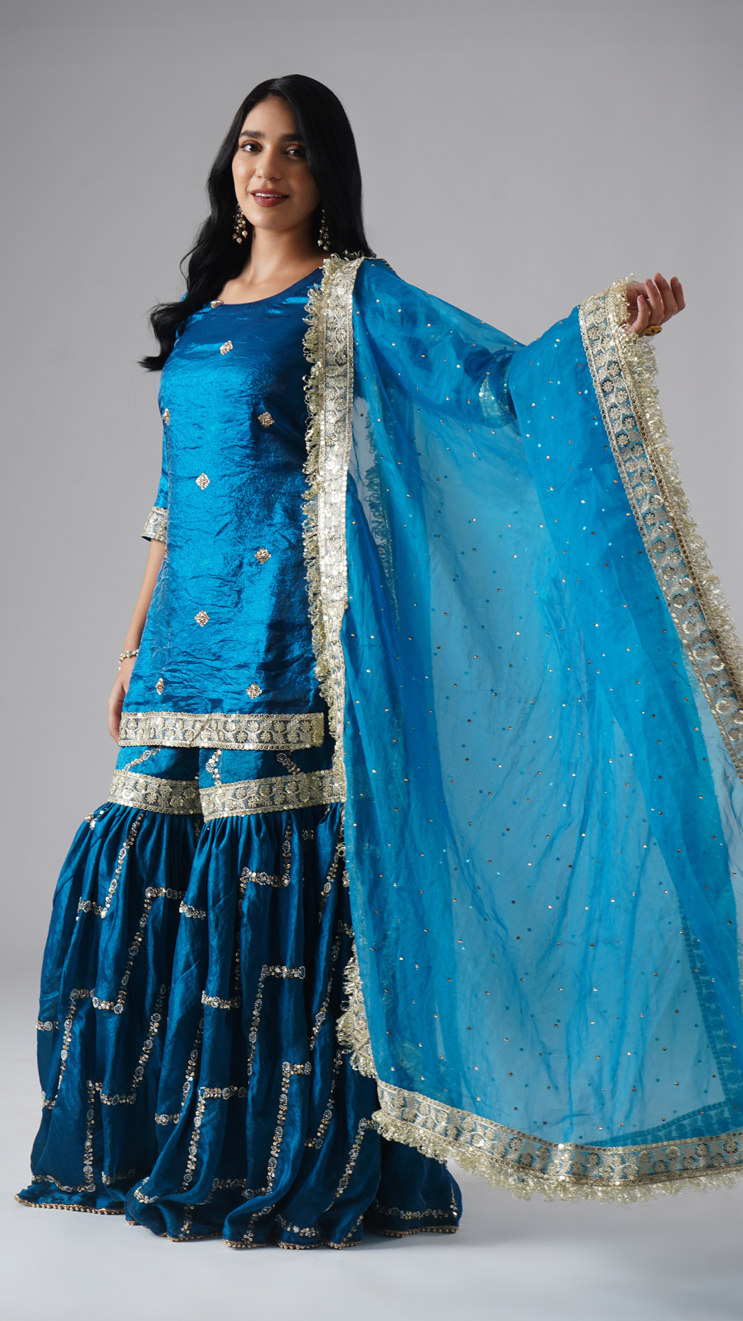 Model styled in the Neelafshan – The Teal Sapphire gharara set by Zahrat, side view highlighting the full-length dupatta and the entire outfit.