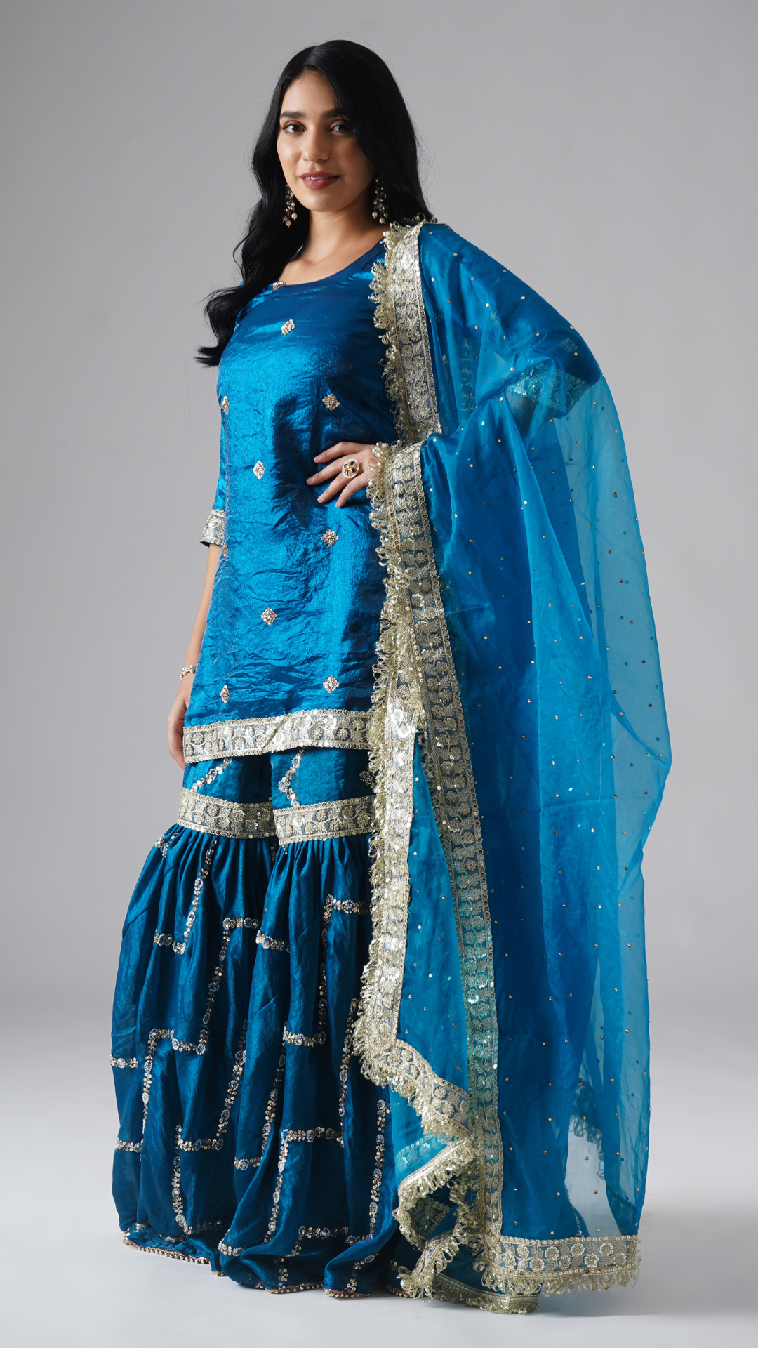 Model styled in the Neelafshan – The Teal Sapphire gharara set by Zahrat, left side view highlighting the draped dupatta and full outfit.