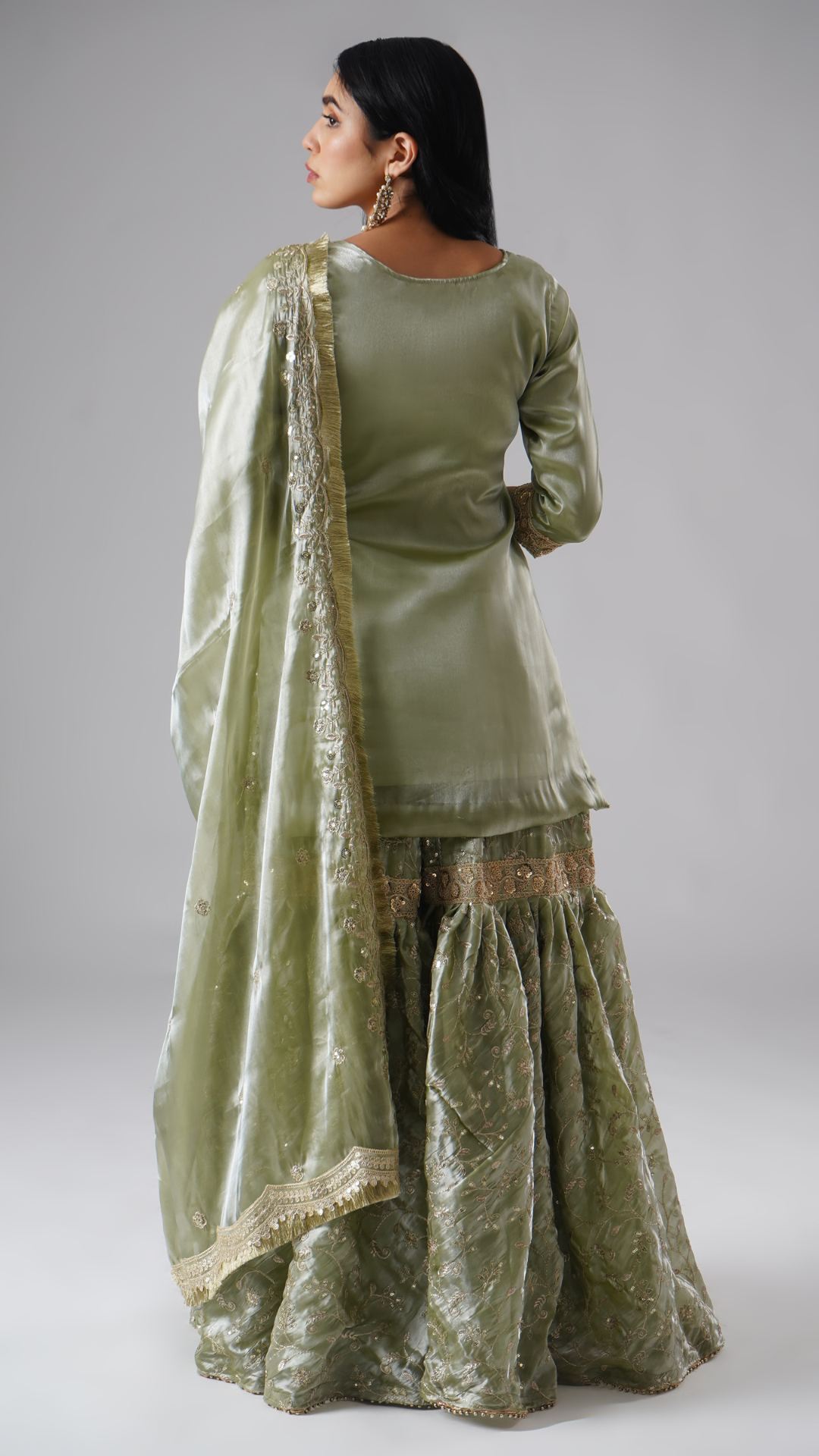 Model styled in the Mehr-e-Zaytuni – The Olive Whisper gharara set by Zahrat, back view highlighting the full outfit and draped dupatta.