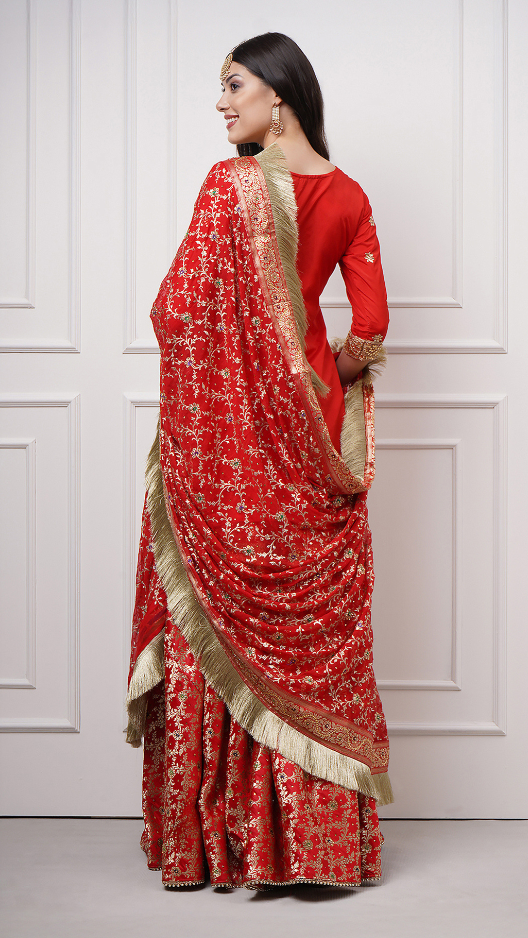 A women models in Surkhnaaz – Red Kimkhwab Bridal Gharara Set by Zahrat backside view.