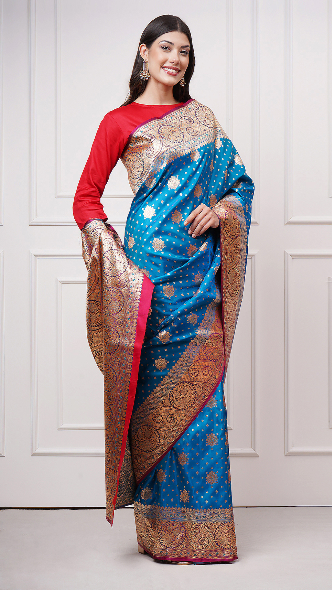 A woman models in Taraani – Midnight Sapphire Saree by Zahrat. A blue and gold Banarasi saree. - front right view.
