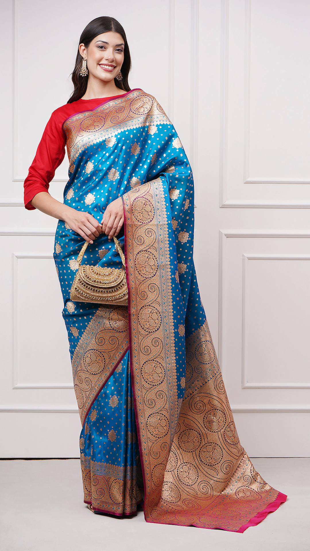 A woman models in Taraani – Midnight Sapphire Saree by Zahrat. A blue and gold Banarasi saree. - A lifestyle shot.