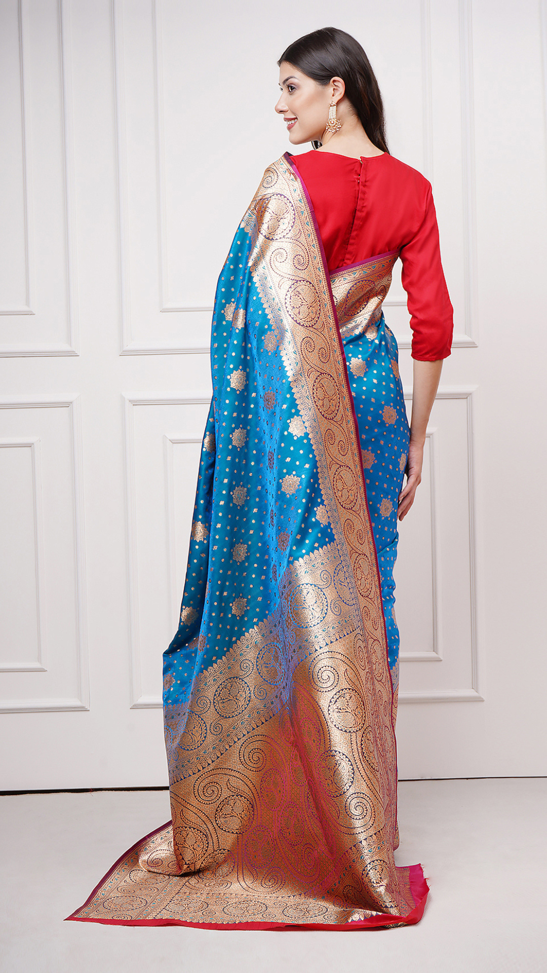 A woman models in Taraani – Midnight Sapphire Saree by Zahrat. A blue and gold Banarasi saree. - backside view showcasing the gold zari pallu.