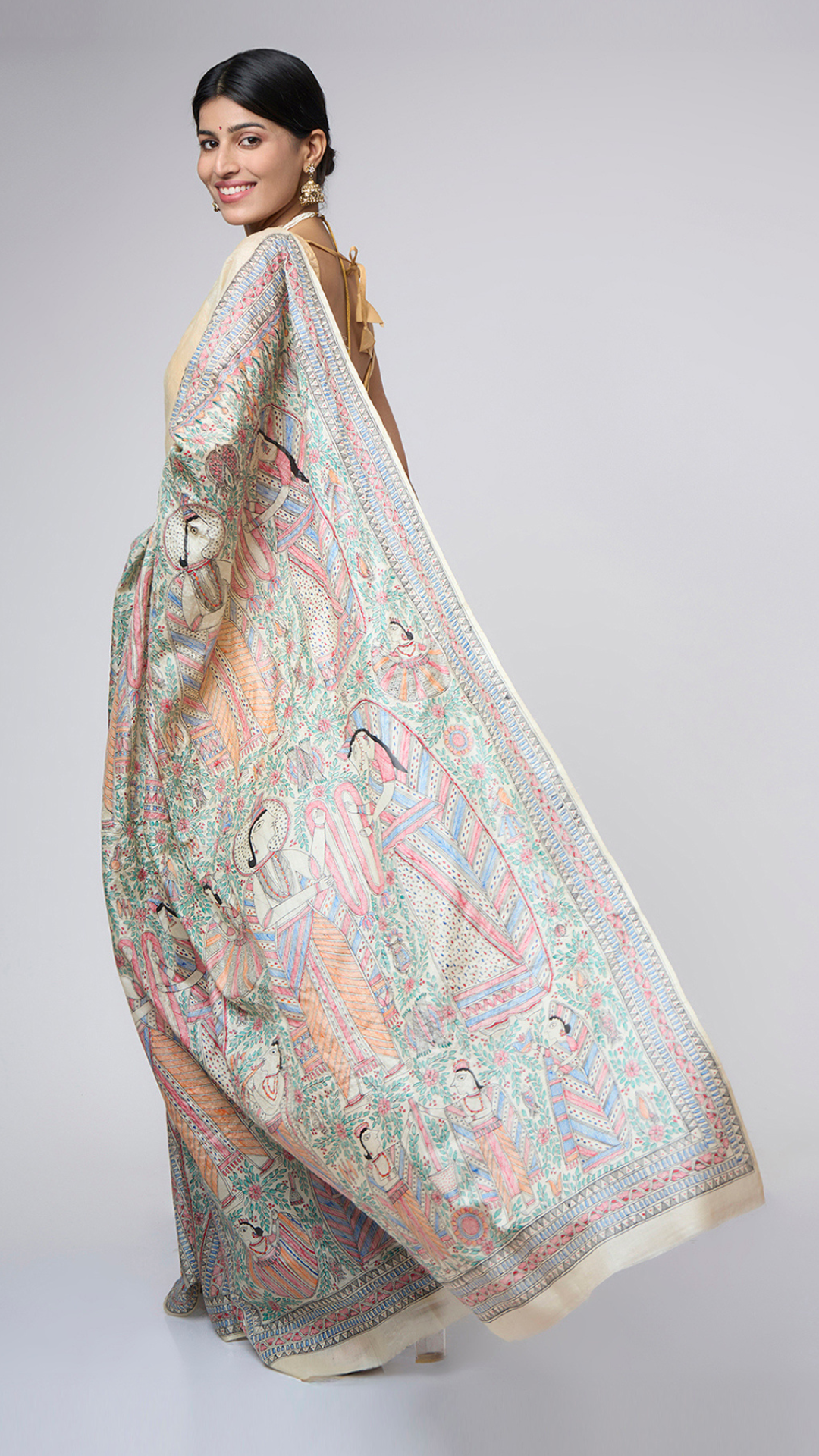 Full back view of Varnika Sand Ivory Madhubani silk saree displaying the detailed all-over hand-painted pallu inspired by traditional wedding storytelling art.