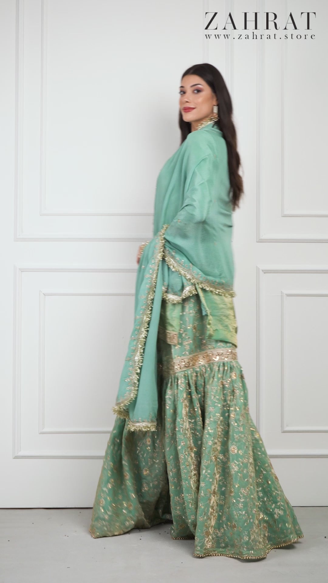 Video of a model wearing the Zahrat Nooraniya – Pastel Jade Gharara Set, walking gracefully and twirling to showcase the fluid flare of the gharara pants. The pastel jade-green fabric shimmers softly under the light, revealing delicate tone-on-tone embroidery on both the kurta and gharara for an elegant, festive look.