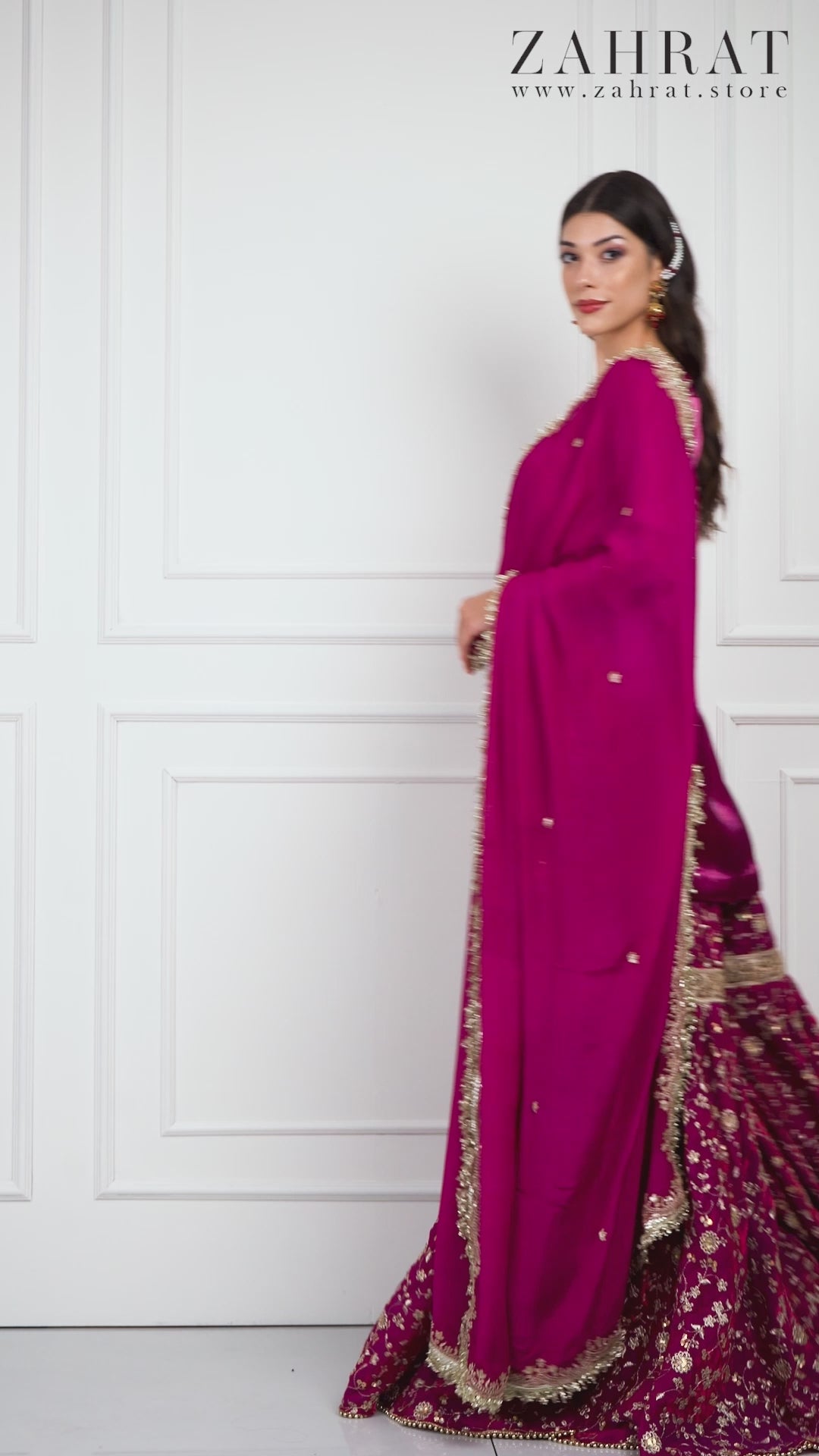 Video of a model wearing the Zahrat Raina – Fuchsia Bloom Gharara Set, walking and twirling to reveal the gharara’s voluminous flare, shimmering gota embroidery, and the graceful movement of the golden-edged dupatta.