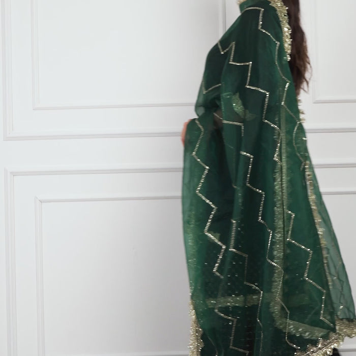 Video of a model wearing the Zahrat Esmeriya Gharara Set, walking and twirling to reveal the gharara’s voluminous flare, shimmering gold embroidery, and soft flow of the coordinating dupatta.