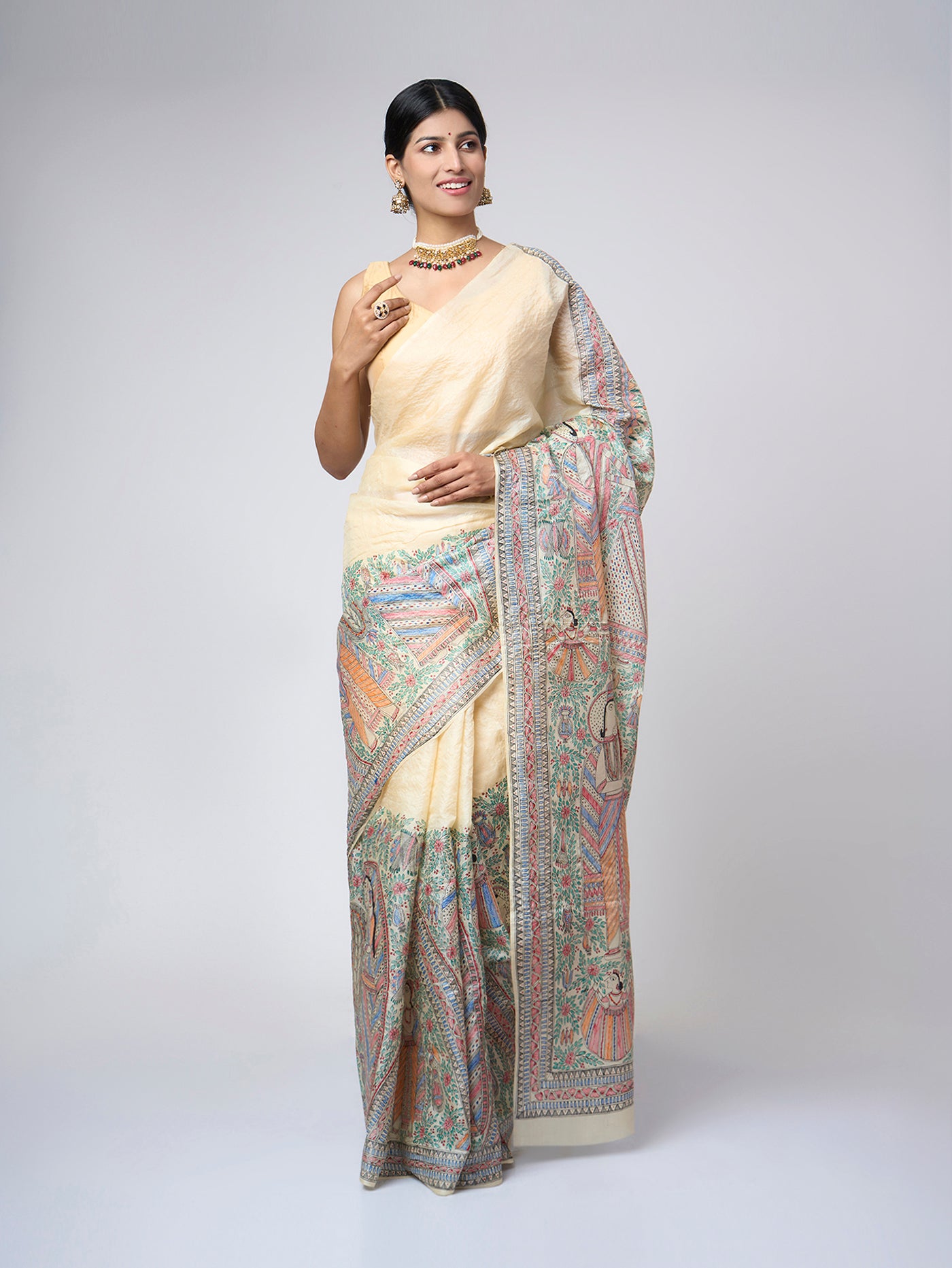 Model wearing Varnika Sand Ivory Madhubani silk saree with an elegant front drape and intricate hand-painted heritage artwork.