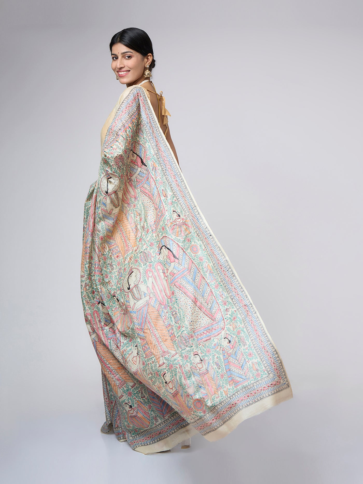 Full back view of Varnika Sand Ivory Madhubani silk saree displaying the detailed all-over hand-painted pallu inspired by traditional wedding storytelling art.